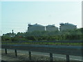 M49, trees by the motorway, power lines and gas tanks in the distance