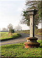 TG2905 : View west along Kirby Road past Bramerton village sign by Evelyn Simak