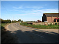 The B1105 road past a barn by the junction with Hand Lane