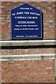 Noticeboard and benchmark on St John the Baptist Church