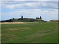 NU2422 : Looking across the golf course towards Dunstanburgh Castle by Graham Robson