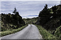 NG7815 : Road cutting with view of Eigg by Peter Moore