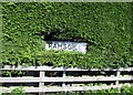 Village  sign  almost  lost  in  the hedge