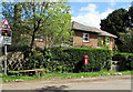 Postbox on a stand at the edge of a hedge, West Dean