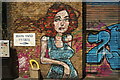 View of a street art of a woman in a dress on the front of a garage on Wallis Road