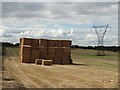 Stack of bales and a pylon near Beech Farm