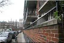 TQ3480 : View along the brick wall in front of a block of flats on Wellclose Square by Robert Lamb