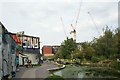 View of a wall of street art and apartments and cranes on Fish Island from the Hertford Union Canal towpath