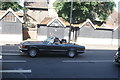 View of a Mercedes 350SL pulling away from the traffic lights at Eltham Church on Well Hall Road