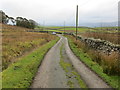 Minor road between stone wall and open land near Parc-newydd