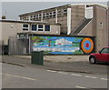 Dark green cabinet near a colourful mural, Evans Street, Newport