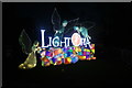 View of the illuminated Lightopia sign by the Dukes Avenue entrance gate of Chiswick House and Gardens