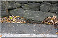 Benchmark on stone at base of wall on east side of A6033