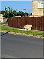 Yellow box alongside a wooden fence, Meadow Road, Stonehouse