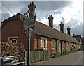 Almshouses, High Street, Much Hadham, with village sign.