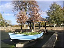 NT9349 : Flower bed boat and shelter in the village of Horncliffe by Walter Baxter