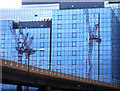 Cranes reflected in a wall of glass