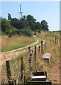 Rising track near derelict cottage, with old wind turbine