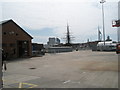 Looking across an empty car park within Portsmouth Dockyard to HMS Victory